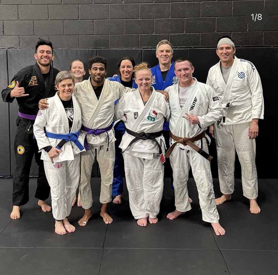 Adult WDC BJJ students of all belt levels smiling together on the mats after class
