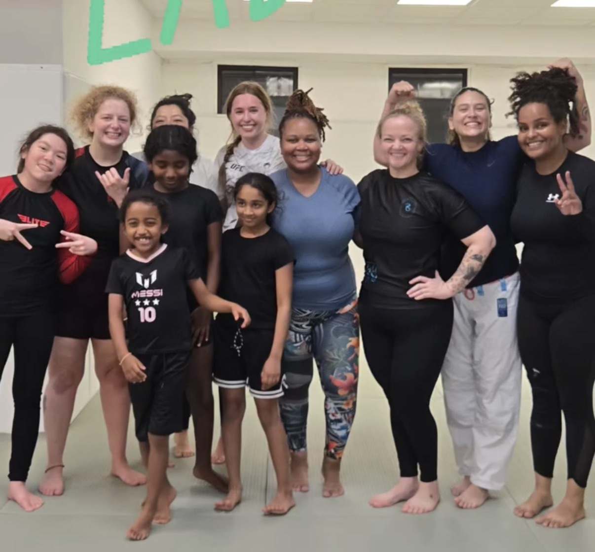 Women and girls from the WDC BJJ women's class posing together on the mats